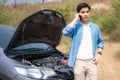 Asian young unhappy man talking on a cell phone  in front of the open hood  broken down car On Country Road Phoning For Help. Royalty Free Stock Photo