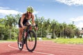 Asian young woman athletes cycling on a race track intently at outdoor sports field on bright day