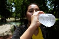 Asian young woman in black and yellow sportwear Thirsty and resting and drinking water in bottle after exercise and running. Royalty Free Stock Photo