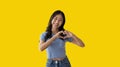 Asian young woman with bright smile making heart symbol shape with hands Royalty Free Stock Photo