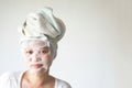 Asian Young woman with delighted expression, applies natural beauty product mask sheet on face