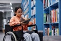 Asian young woman with disability reading book in library Royalty Free Stock Photo