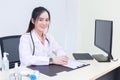 Asian young woman doctor in a white lab coat is sitting on office room at hospital Royalty Free Stock Photo