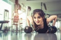 Asian young woman doing push ups with dumbbell on floor in fitness gym and equipment background. Workout and Sport Exercise Royalty Free Stock Photo