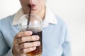 Asian young woman drinking iced black coffee in a plastic cup,take away package,using plastic straws to drink beverage,concept of