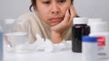 Asian young woman feeling sick sitting looking at a lot of pills.