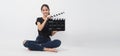 Asian young woman holding black clapper board or movie slate or clapboard and sit on thefloor .it use in video production ,film, Royalty Free Stock Photo