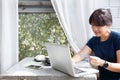 Asian young woman holding credit card and using laptop computer while sitting in cafe. Online shopping concept. Copy space. Royalty Free Stock Photo