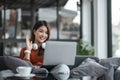 asian young woman listening music with headphone and streaming music from laptop on sofa relaxing at home Royalty Free Stock Photo