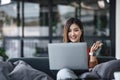 asian young woman listening music with headphone and streaming music from laptop on sofa relaxing at home Royalty Free Stock Photo