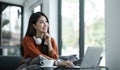 asian young woman listening music with headphone and streaming music from laptop on sofa relaxing at home Royalty Free Stock Photo