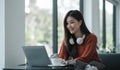 asian young woman listening music with headphone and streaming music from laptop on sofa relaxing at home Royalty Free Stock Photo