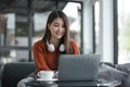 asian young woman listening music with headphone and streaming music from laptop on sofa relaxing at home Royalty Free Stock Photo