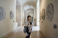 Asian young woman looking around the Louvre Museum and appreciating the beauty of a work of art.