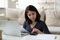 Asian young woman manage household finances using laptop