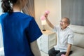 Asian young woman nurse at home nursing care support disabled senior elderly man. Caregiver Therapist serve physical therapy for o Royalty Free Stock Photo