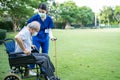 Asian young woman nurse at nursing home take care and support disabled senior elderly man on walker or cane at backyard. Caregiver Royalty Free Stock Photo