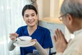 Asian young woman nurse at nursing home taking care of disabled senior elderly man on wheelchair. Beautiful Therapist doctor Royalty Free Stock Photo
