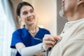 Asian young woman nurse at nursing home taking care of disabled senior elderly man on wheelchair. Therapist doctor measure heart r