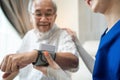 Asian young woman nurse at nursing home taking care of senior elderly man sit on sofa. Caregiver Therapist doctor examining an old Royalty Free Stock Photo