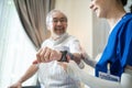 Asian young woman nurse at nursing home taking care of senior elderly man sit on sofa. Caregiver Therapist doctor examining an old Royalty Free Stock Photo