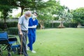 Asian young woman nurse taking care and support disabled senior elderly man on wheelchair at backyard. Caregiver doctor and older Royalty Free Stock Photo