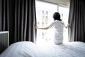 Asian young woman opening curtain and window for hygienic,sunlight to enter her bedroom and air circulate freely in room at home,