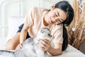 Asian young woman play with the fur little cat with happiness at home. Beautiful female sit on bed, spend leisure time stroking Royalty Free Stock Photo