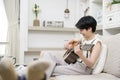 Asian young woman is playing guitar on sofa at home , happy relaxing lifestyle concept Royalty Free Stock Photo