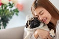 Asian young woman playing with her pet and smile with pug dog