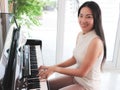 Asian young woman playing piano upright in the white room Royalty Free Stock Photo