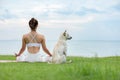 Asian young woman practice yoga lotus pose to meditation with dog on the beach feeling so happiness and cheerful Royalty Free Stock Photo