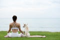 Asian young woman practice yoga lotus pose to meditation with dog on the beach feeling so happiness and cheerful Royalty Free Stock Photo