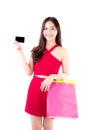 Asian young woman with red dress holding a credit card and paper bag. Royalty Free Stock Photo