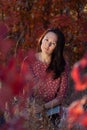 Asian young woman in red dress reads open book in grass in autumn forest at sunset