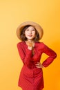 Asian young woman send air kiss. Girl wearing red dress and brown hat over orange background Royalty Free Stock Photo
