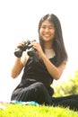 Asian young woman sit on mound seeking binoculars . Royalty Free Stock Photo