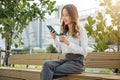 Asian young woman sitting on bench outdoor on park using smart mobile phone Royalty Free Stock Photo