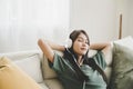 Asian young woman sitting on sofa. Happy female listening music and sleeping in living room Royalty Free Stock Photo