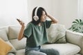 Asian young woman sitting on sofa. She listening music and dancing in living room Royalty Free Stock Photo