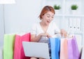 Asian young woman sitting on sofa with shopping bags using laptop computer to online shopping Royalty Free Stock Photo