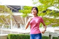 Asian young woman smiling beautiful and healthy Jogging outdoors in a city park. Royalty Free Stock Photo