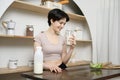 Asian young woman in sportswear drinking milk in kitchen at home , healthy lifestyle concept Royalty Free Stock Photo