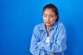 Asian young woman standing over blue background shaking and freezing for winter cold with sad and shock expression on face Royalty Free Stock Photo