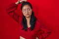 Asian young woman standing over red background confuse and wondering about question Royalty Free Stock Photo