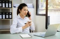 Asian young woman talk mobile phones and working on laptop computers Royalty Free Stock Photo