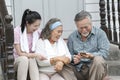 Asian young woman teach `how to used mobile for online shoping` older father and mother in outdoor terrace house. -lovely family c Royalty Free Stock Photo