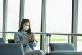 Asian young woman traveller wearing face maks using mobile phone at airport