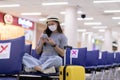 Asian young woman traveller wearing face maks using mobile phone at airport