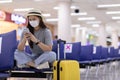 Asian young woman traveller wearing face maks using mobile phone at airport